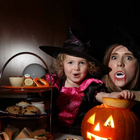 Family enjoying Halloween treats with lit pumpkins at a Hastings Hotel.