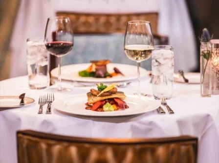 Elegant dining table set with gourmet dishes and wine in a cosy hotel restaurant.