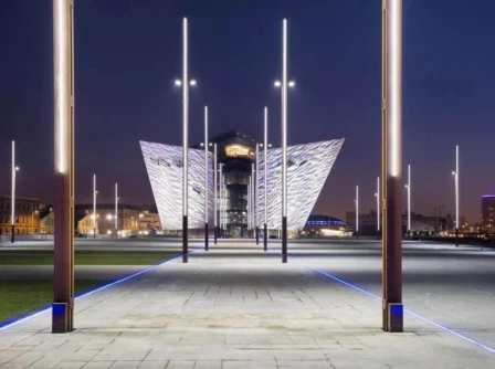 Family strolls under illuminated pathways near a modern architectural marvel.
