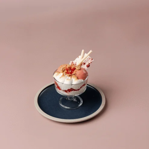 Elegant dessert in a glass dish on a stylish plate, set against soft pink background.
