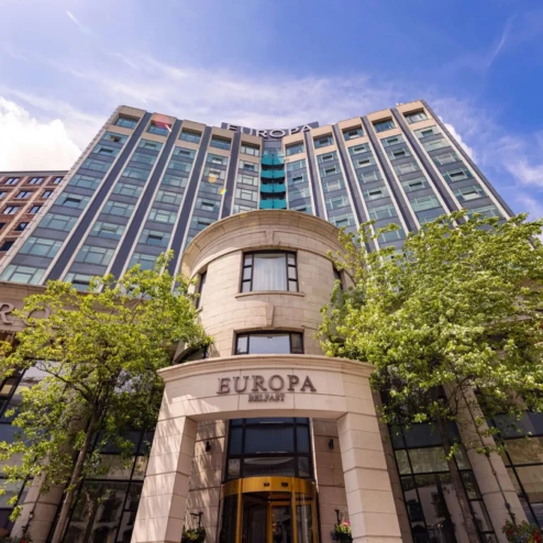 Elegant city hotel facade with lush greenery and blue sky.