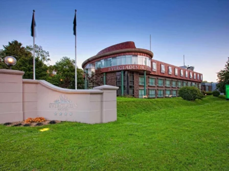 Modern hotel exterior with green lawn and welcoming atmosphere at dusk.