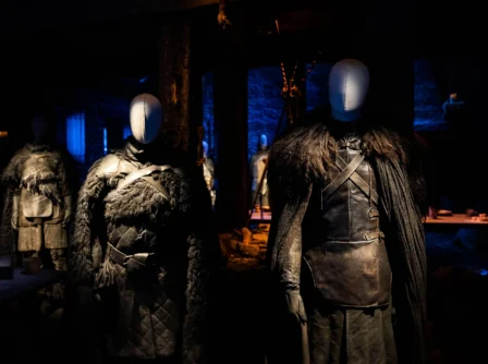 A family explores a dimly lit exhibit featuring medieval costumes.