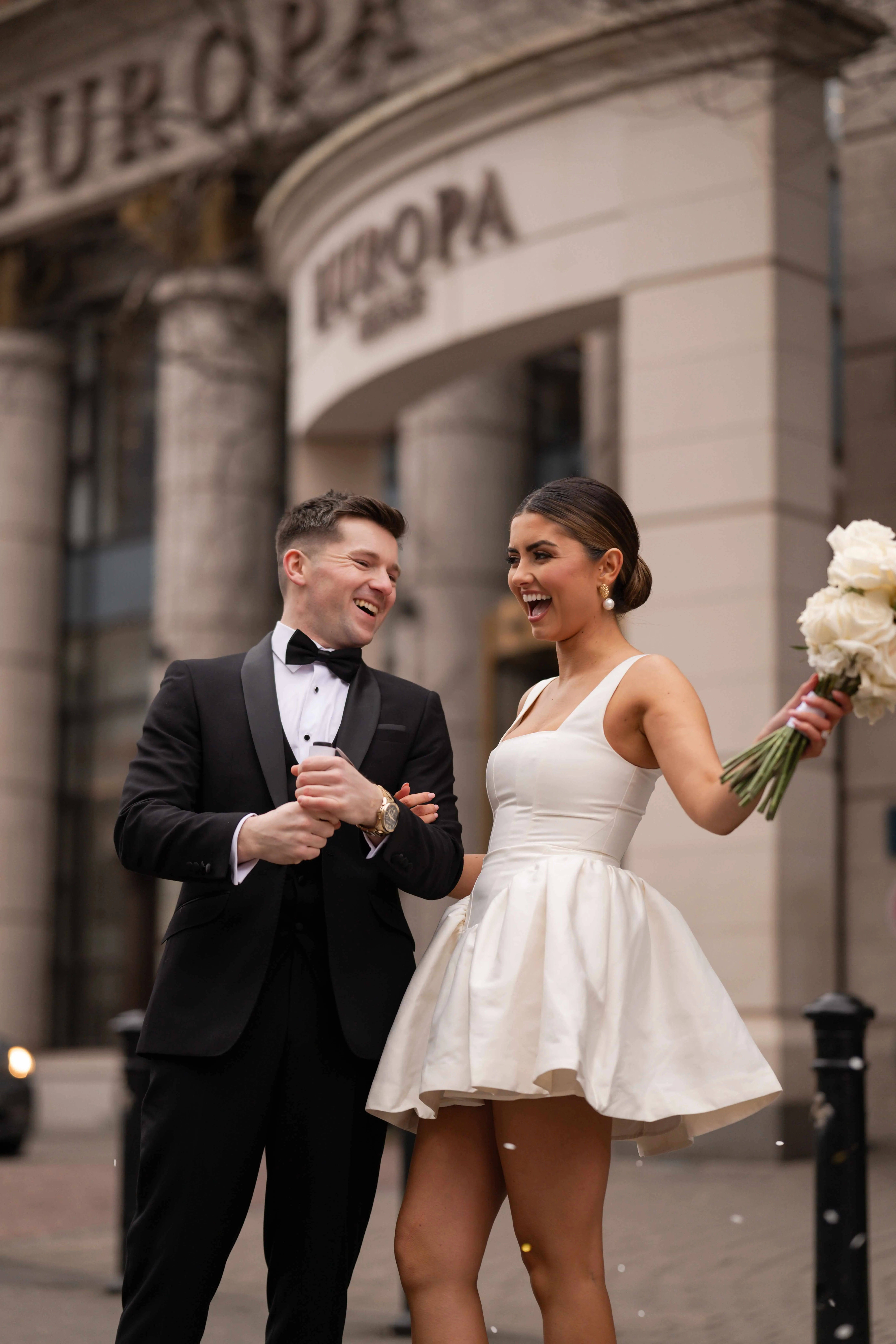 Smiling couple in formal attire outside Europa Hotel.