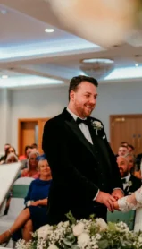 A joyful couple weds in an elegant hotel ceremony room filled with family and friends.