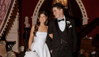 A joyful couple in formal attire in an elegant, chandelier-lit hotel lounge.