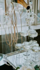 Champagne tower in elegant hotel setting with flowers and candelabra, ready for celebration.